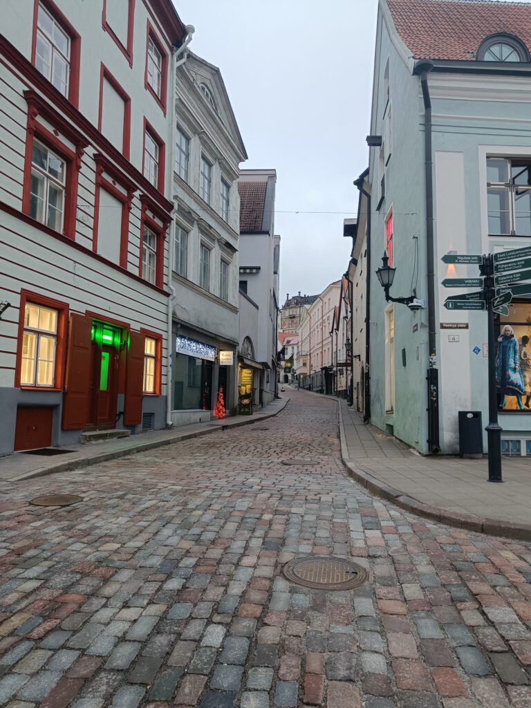 Narrow cobblestone street in Tallinn Old Town, surrounded by colourful historic buildings and traditional lanterns.