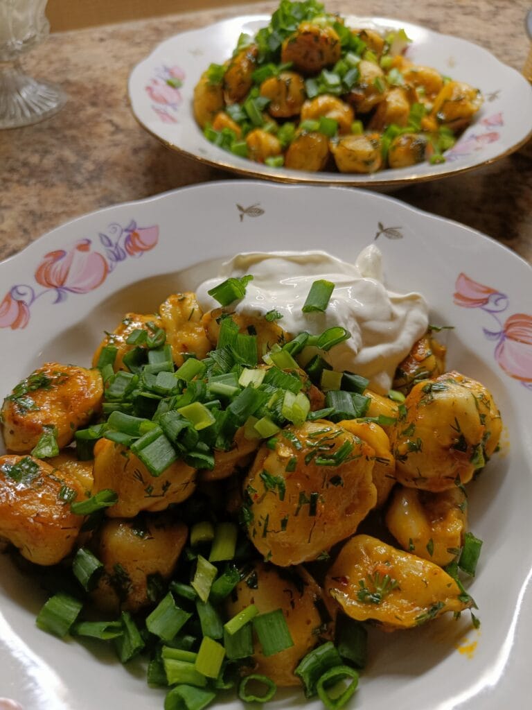 Pan-fried dumplings tossed with herbs and topped with fresh chives and a dollop of sour cream.