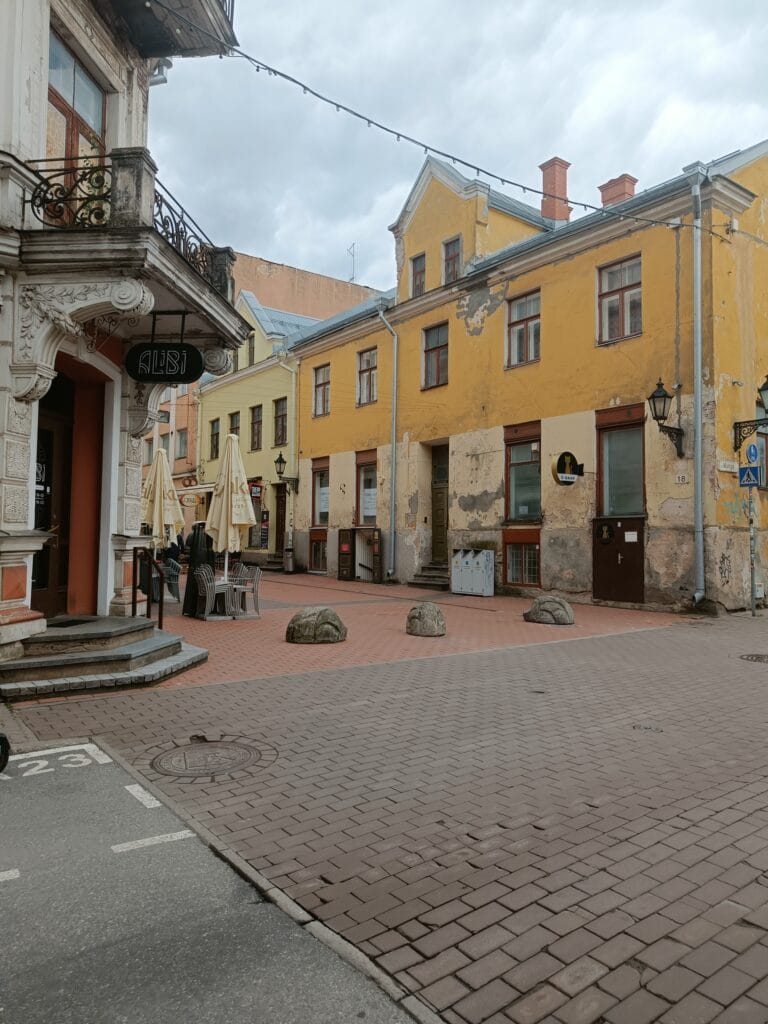 Weathered yellow and cream-coloured historic buildings along a quiet Old Town street in Tartu, showing the mix of restoration and age that gives the city its character.